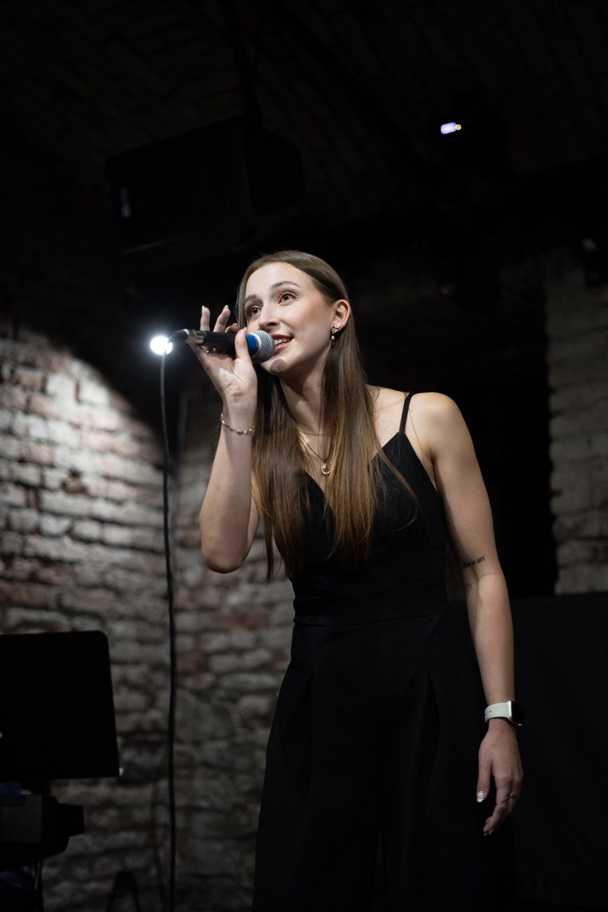 Zpěvačka s mikrofonem na pódiu v Everything Pardubice